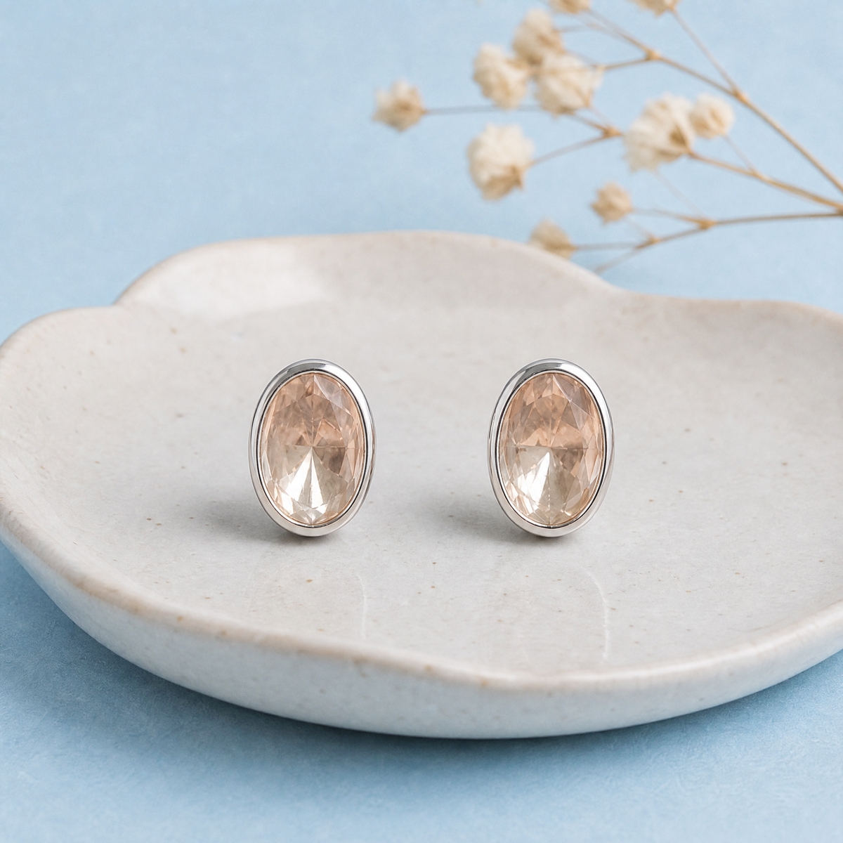 Blush Oval Bezel Stud Earrings in 925 sterling silver, on a ceramic dish