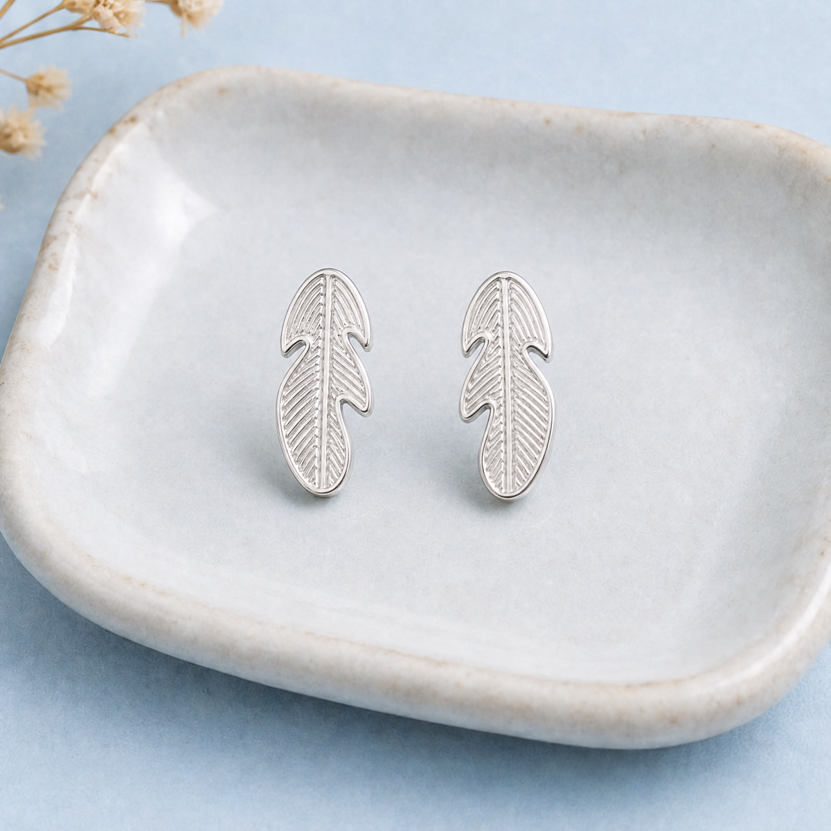 Engraved Feather Stud Earrings in 925 sterling silver, on a ceramic dish