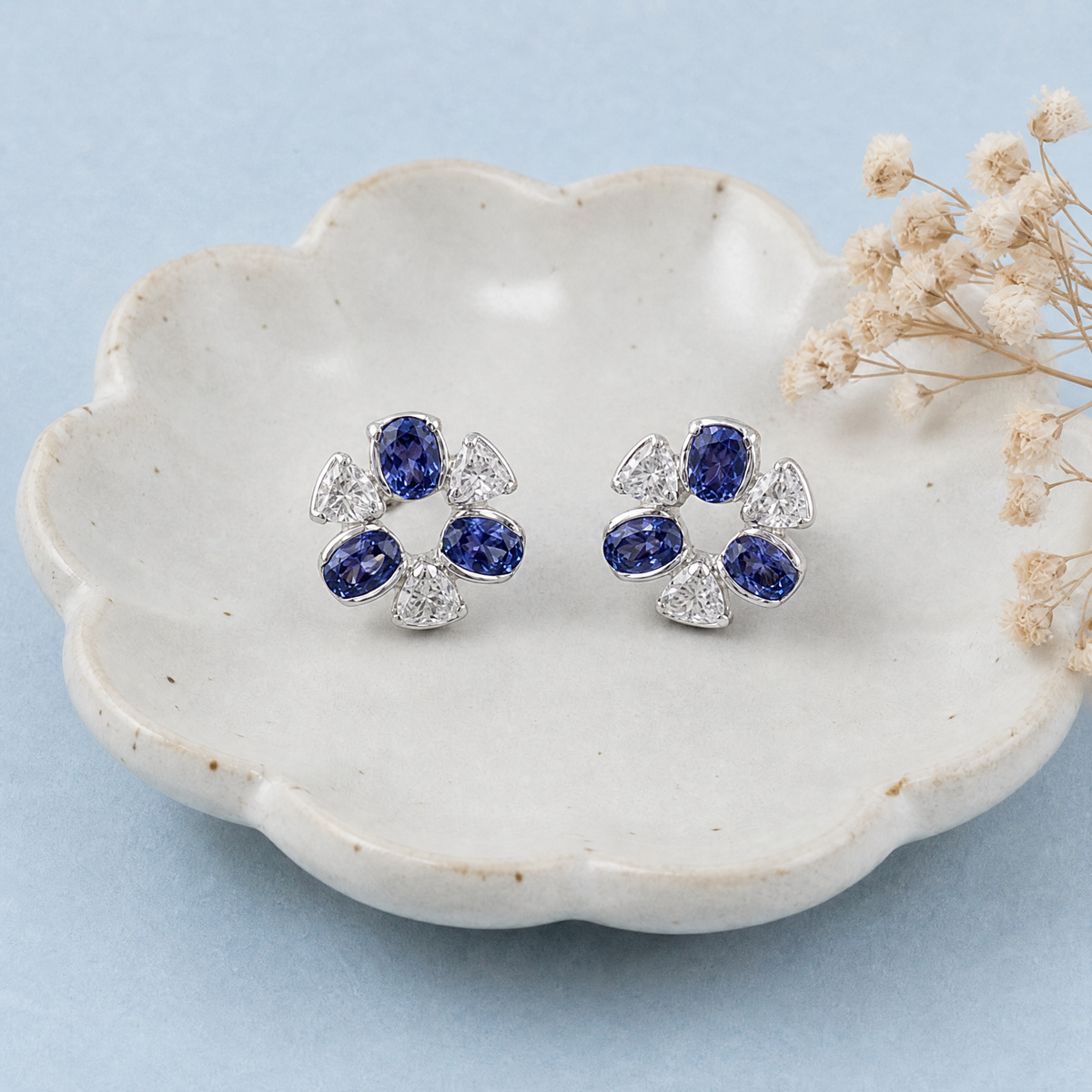 Blue and Clear Flower Stud Earrings in 925 sterling silver, on a ceramic dish
