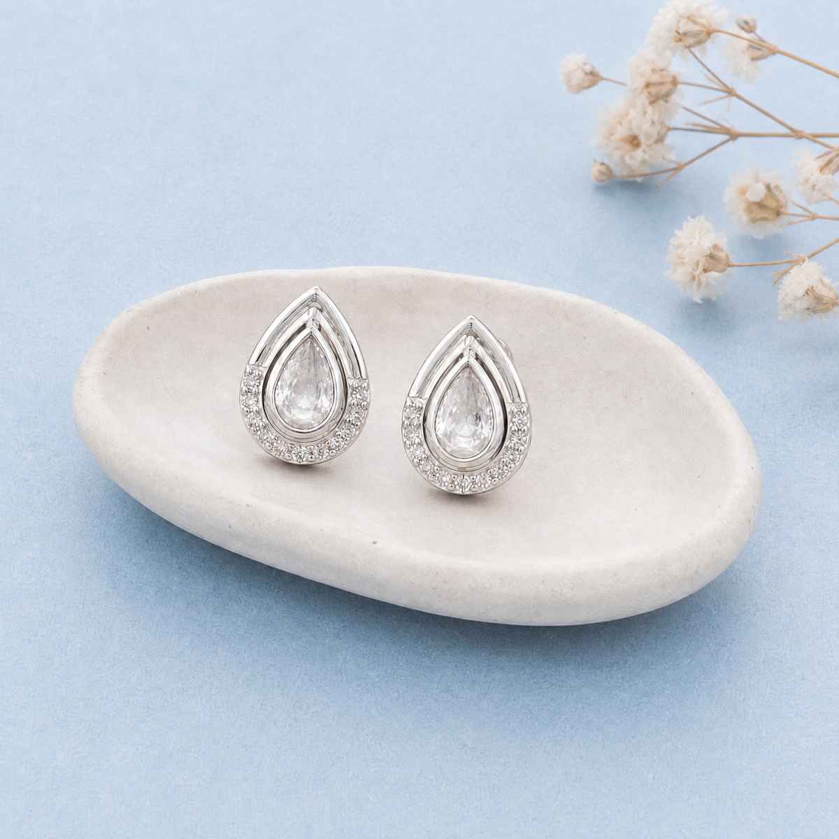 Pear Halo Frame Stud Earrings in 925 sterling silver, on a ceramic dish