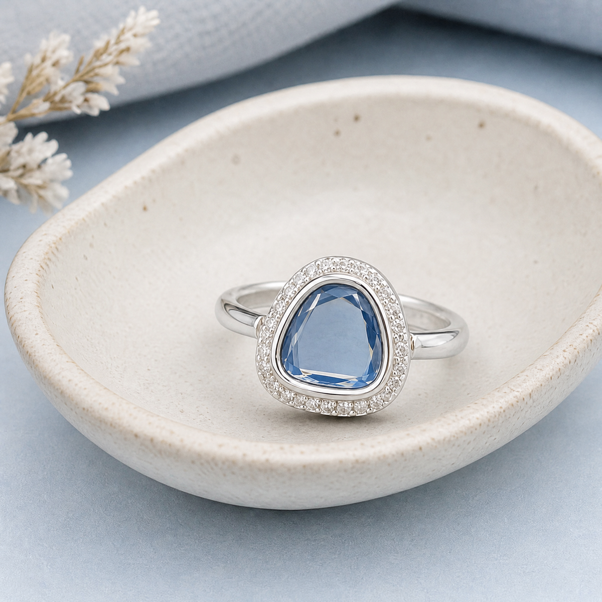 Blue Triangle Halo Ring in 925 sterling silver, in a ceramic dish